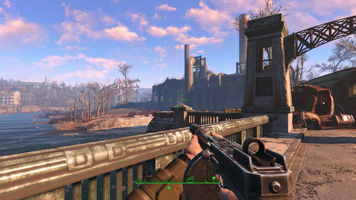 First-person view in Fallout 4: Game of the Year Edition, showing a player aiming a firearm while exploring an industrial area near the water. Rusted buildings and an old bridge highlight the game's atmospheric world. Get your Fallout 4 GOTY CD key for PC (GOG) at RushGame.co today