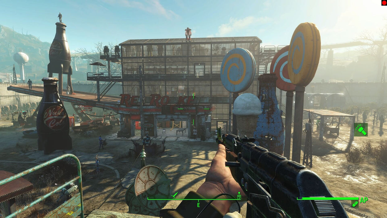 Gameplay screenshot - First-person perspective in Fallout 4: Game of the Year Edition, aiming a weapon at a fortified settlement with a retro-style Red Rocket sign and giant Nuka-Cola bottles. Explore and build in the wasteland—purchase your Fallout 4 GOTY CD key for PC at RushGame.co for instant activation