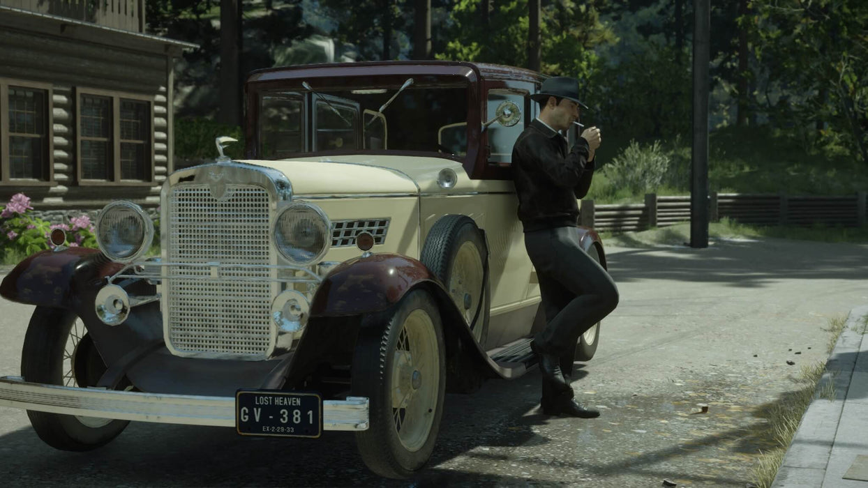 The protagonist leans against a vintage car in Mafia Definitive Edition on PC Steam, taking a brief moment amidst a scenic, forested area. Experience this detailed world by purchasing your Mafia Definitive Edition Steam key at RushGame.co