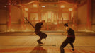 Martial arts battle scene from Sifu on Epic Games, featuring an intense duel in a dojo setting. Get your Sifu Epic Games Key at RushGame.co and immerse yourself in challenging hand-to-hand combat