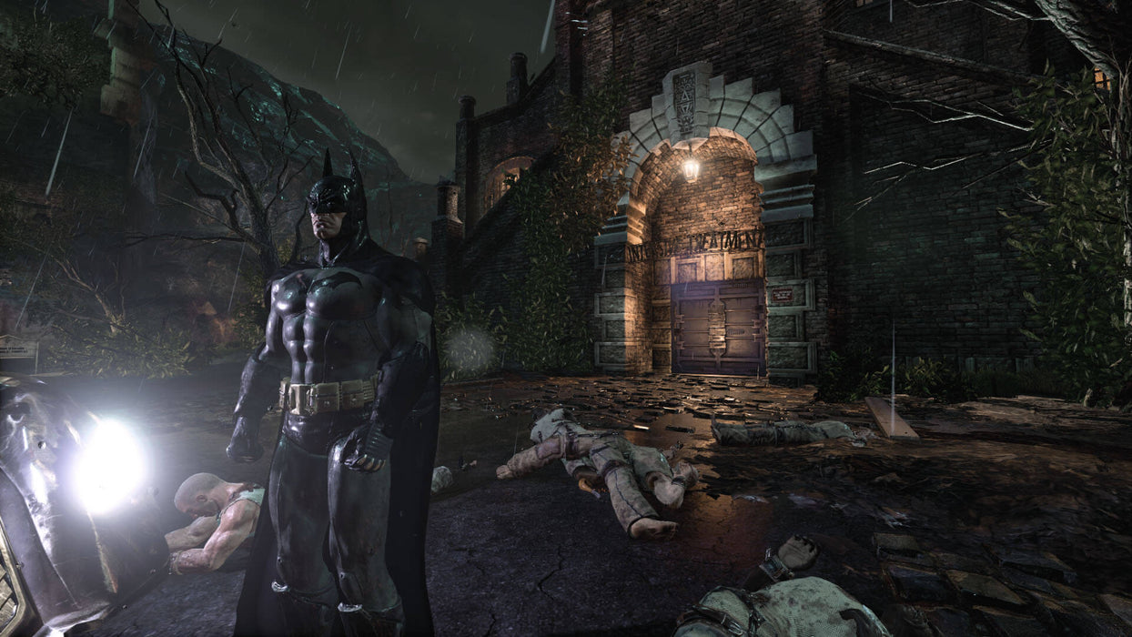 Batman stands in the rain near Arkham Asylum, with defeated enemies lying on the ground in Batman: Return to Arkham for Xbox One. Purchase your Batman: Return to Arkham Xbox One CD Key at RushGame.co and experience the legendary Arkham series remastered
