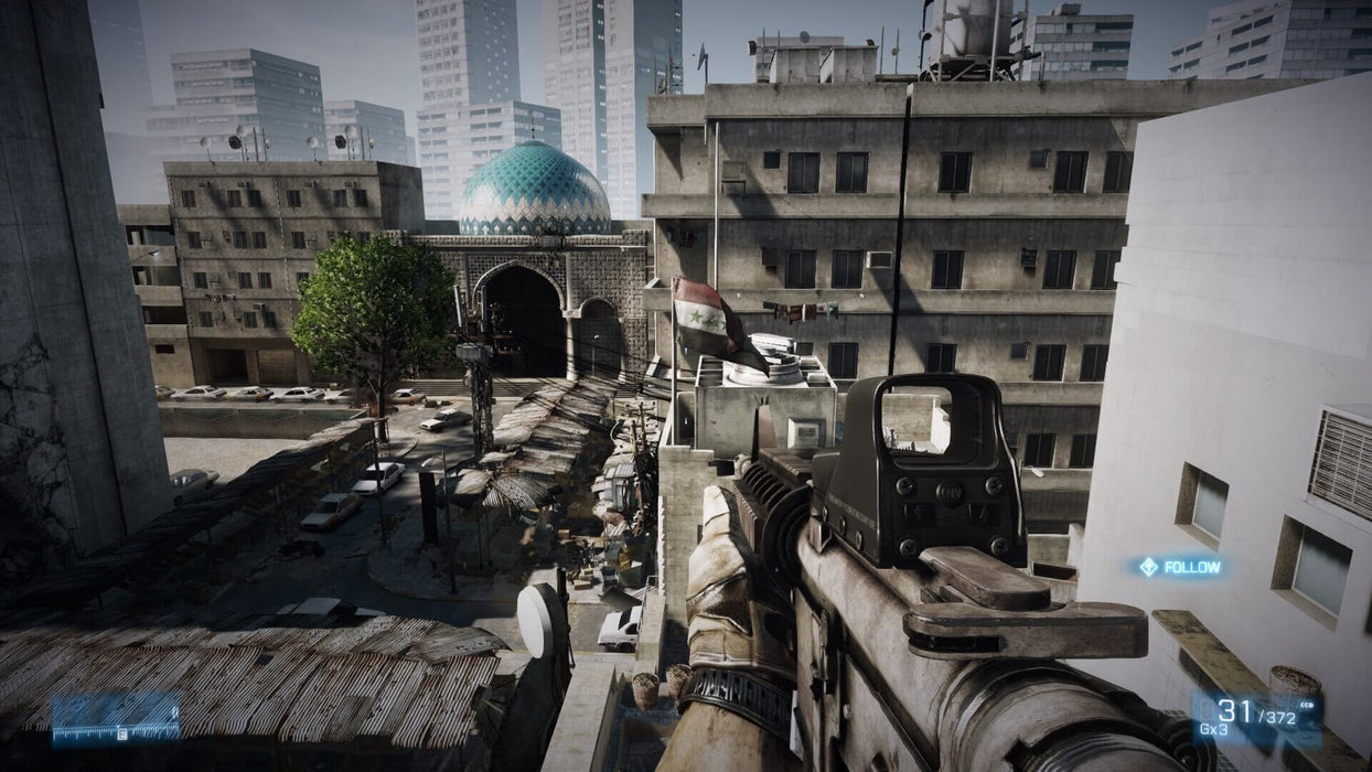 A first-person perspective in Battlefield 3, showing a soldier aiming an assault rifle over a Middle Eastern cityscape. The skyline is dominated by a mosque with a blue dome, while dense urban buildings and a Syrian flag add authenticity to the environment. Get your Battlefield 3 Limited Edition PC EA Play Origin CD Key now at RushGame.co