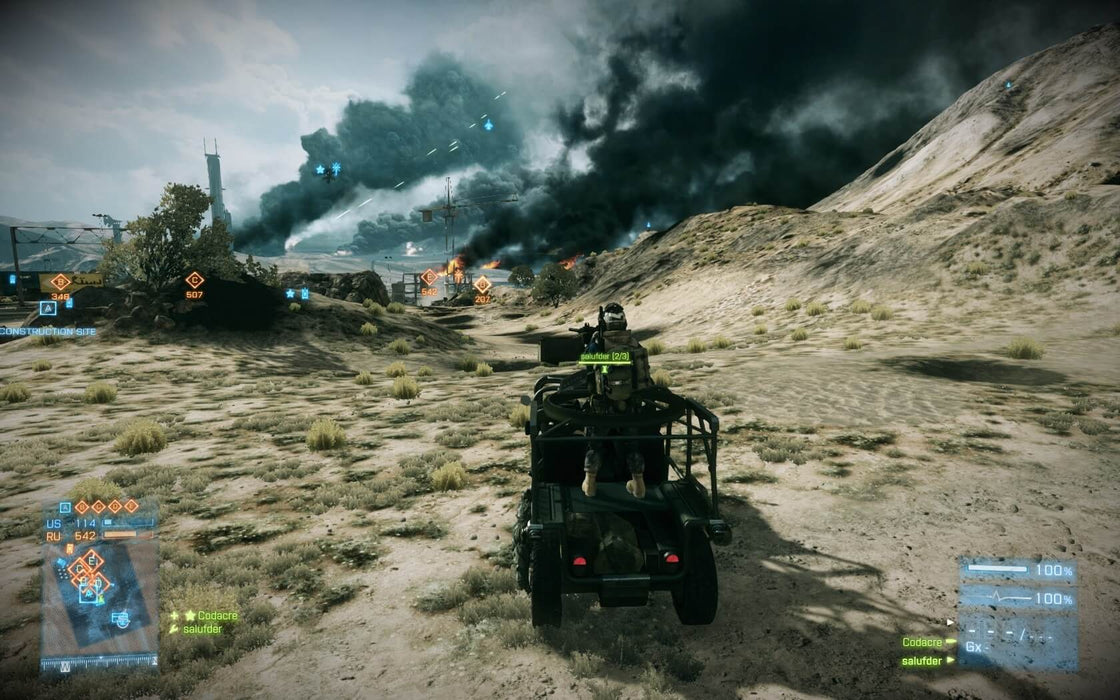  A player-controlled military jeep speeds through a desert battlefield in Battlefield 3. Explosions and black smoke fill the distance, while game HUD elements indicate an ongoing large-scale conflict. Secure your Battlefield 3 Limited Edition PC EA Play Origin CD Key instantly at RushGame.co