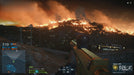 A first-person shooter perspective in Battlefield Hardline, showing a sniper rifle aimed at a massive wildfire engulfing a hill at night. The orange flames contrast with the dark sky as smoke billows upwards, creating an intense battlefield atmosphere