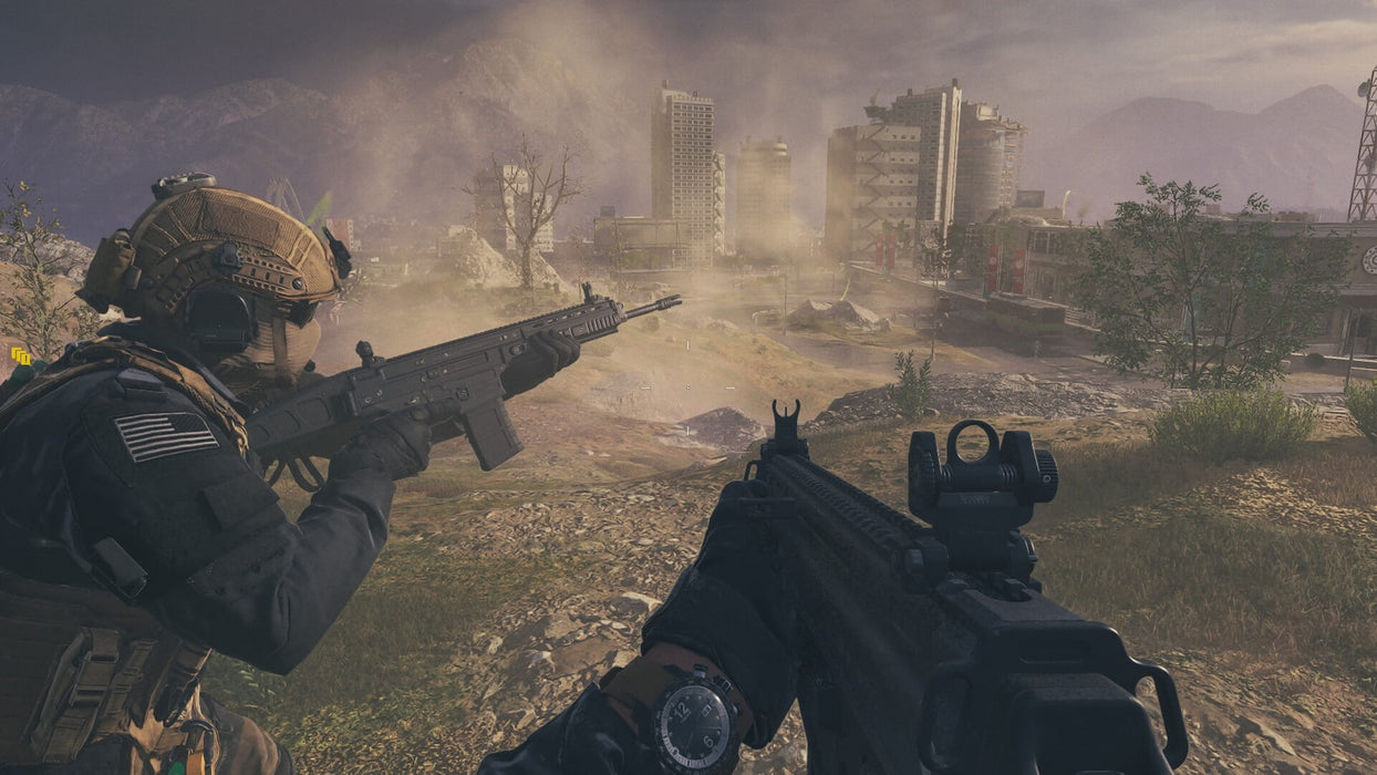 Tactical Combat in Open Terrain – A first-person perspective of a soldier aiming his weapon while another teammate prepares for battle in a dusty battlefield with urban structures in the distance. Secure your Modern Warfare III Cross-Gen Bundle key at RushGame.co and experience high-intensity warfare with realistic combat mechanics.