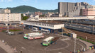 Gameplay screenshot: A bustling transport hub in Cities: Skylines - Mass Transit DLC, featuring a train station, multiple bus stops, and a pedestrian overpass connecting different transport networks. Get your Cities: Skylines Mass Transit activation key from RushGame.co and optimize your city's traffic flow with advanced transit options