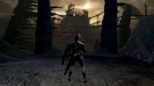 Dark Souls Remastered Gameplay Screenshot – Abyssal Arena Entrance – A lone warrior stands at the threshold of a ruined, foreboding coliseum under a dark sky. The atmospheric visuals highlight the grim world of Dark Souls Remastered. Secure your Steam activation key now at RushGame.co