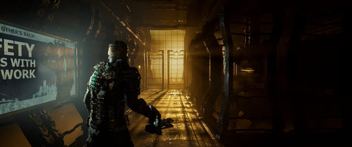 Dead Space Remake PC Steam Screenshot  – The protagonist, Isaac Clarke, walks through a dark metallic corridor bathed in golden lighting, with a sign on the wall reading "Safety Begins with Teamwork." The atmosphere is tense, reinforcing the survival horror theme. Available at RushGame.co