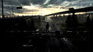 Deadlight: Director’s Cut cinematic scene – A silhouette of the main character stands on top of a highway sign, overlooking an abandoned road stretching into the distance at dusk. The moody lighting and cinematic atmosphere reflect the game’s survival-horror themes. Buy the game now at RushGame.co