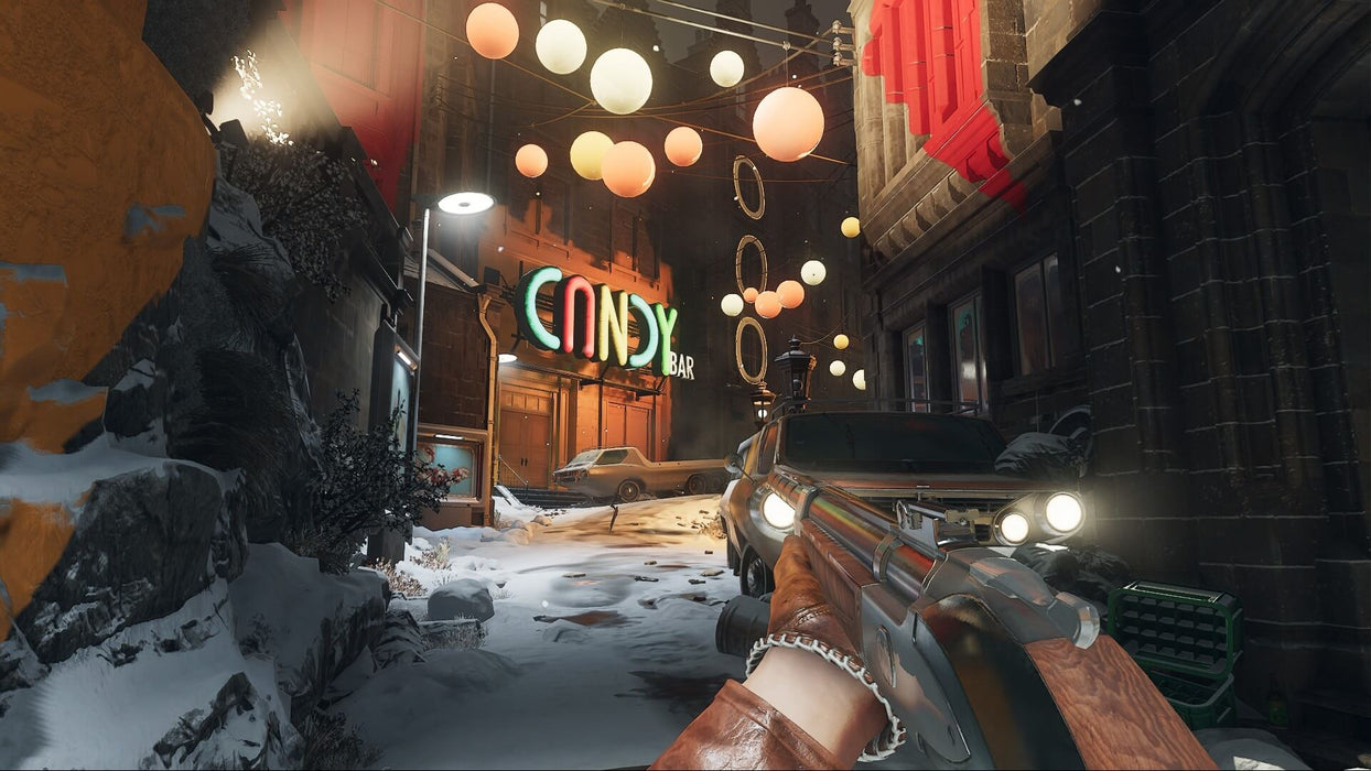 gameplay screenshot: First-person gameplay in Deathloop – A nighttime city scene with glowing neon signs and festive lights illuminating a snow-covered street. The player's perspective shows a shotgun in hand, highlighting the game's unique 1960s-inspired aesthetic. Purchase Deathloop at RushGame.co