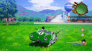 Gameplay image - Vegeta and Trunks riding a futuristic green hover car across the open grasslands, with Capsule Corporation buildings in the background. Explore vast open-world environments in DRAGON BALL Z: Kakarot Legendary Edition, available at RushGame.co