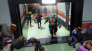 Gameplay screenshot - A tense scene from Evil Genius 2: World Domination for PC Steam, featuring an elite squad of henchmen storming a hallway as panicked guards and scientists scramble. Secure your Steam CD key now at RushGame.co