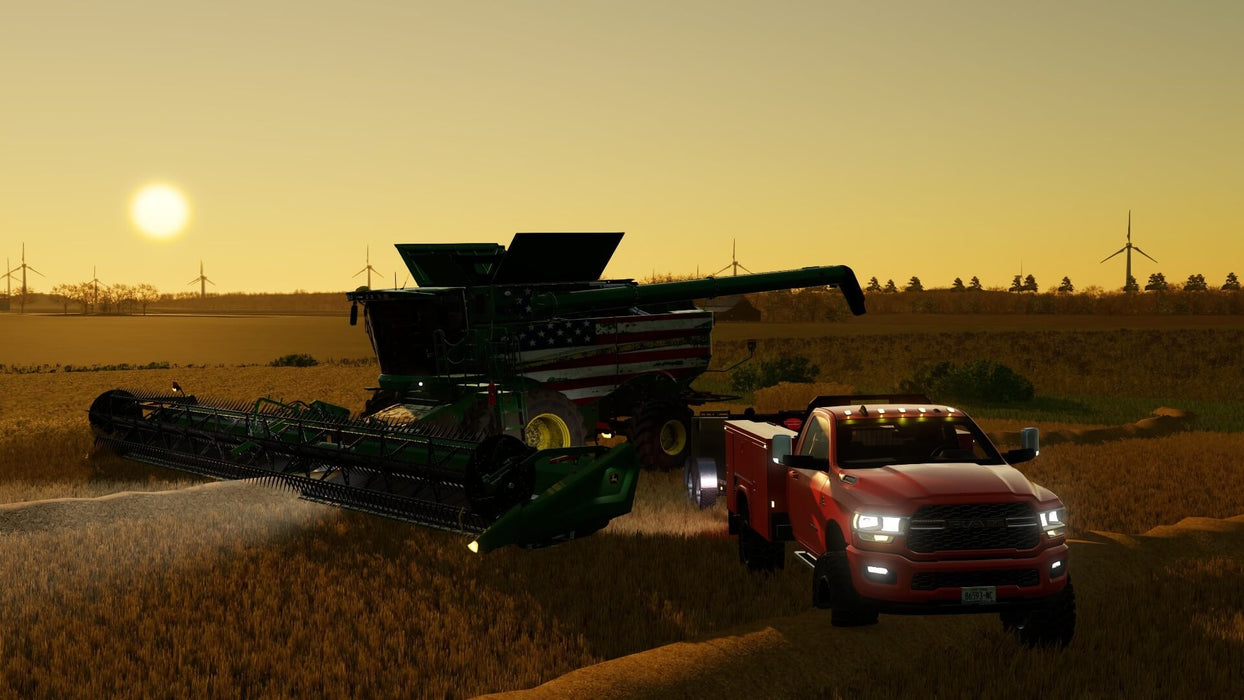 Gameplay screen - A massive harvester with an American flag design and a red pickup truck working together in a golden wheat field at sunset in Farming Simulator 22: Premium Edition. Experience realistic farming with your Steam CD Key from RushGame.co!