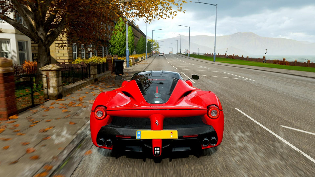 Gameplay screenshot - A red Ferrari LaFerrari speeding through the streets in Forza Horizon 4 Ultimate Edition, showcasing the game's realistic car physics and dynamic weather effects. Get your instant game key for Xbox One and Windows 10 at RushGame.co and start your ultimate racing adventure