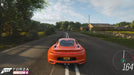 In-game screenshot from Forza Horizon 4 Ultimate Edition, showing a sleek orange Saleen S1 speeding down a rural British road. Buy your Forza Horizon 4 game key now at RushGame.co for an exhilarating open-world racing experience
