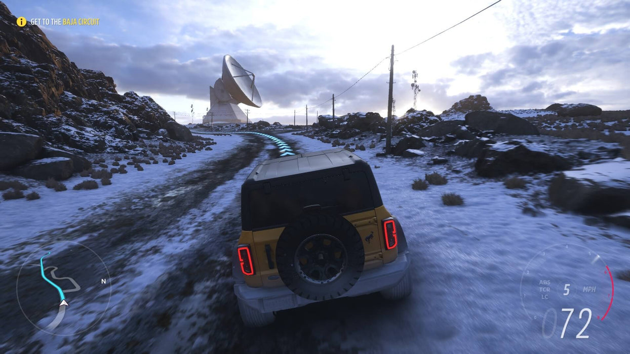 Gameplay screenshot -  A yellow Ford Bronco navigating a snowy mountain road in Forza Horizon 5, heading towards a massive satellite dish. Explore diverse terrains and race through extreme weather with Forza Horizon 5 Standard Edition—available now at RushGame.co