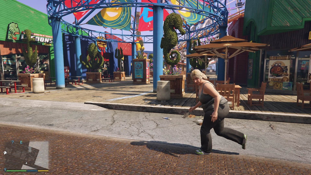 Gameplay screenshot - A vibrant daytime scene from Grand Theft Auto V for Xbox One, showing a lively amusement park with colorful decorations and a pedestrian walking by. Explore the dynamic city of Los Santos with your GTA V Xbox One CD Key from RushGame.co