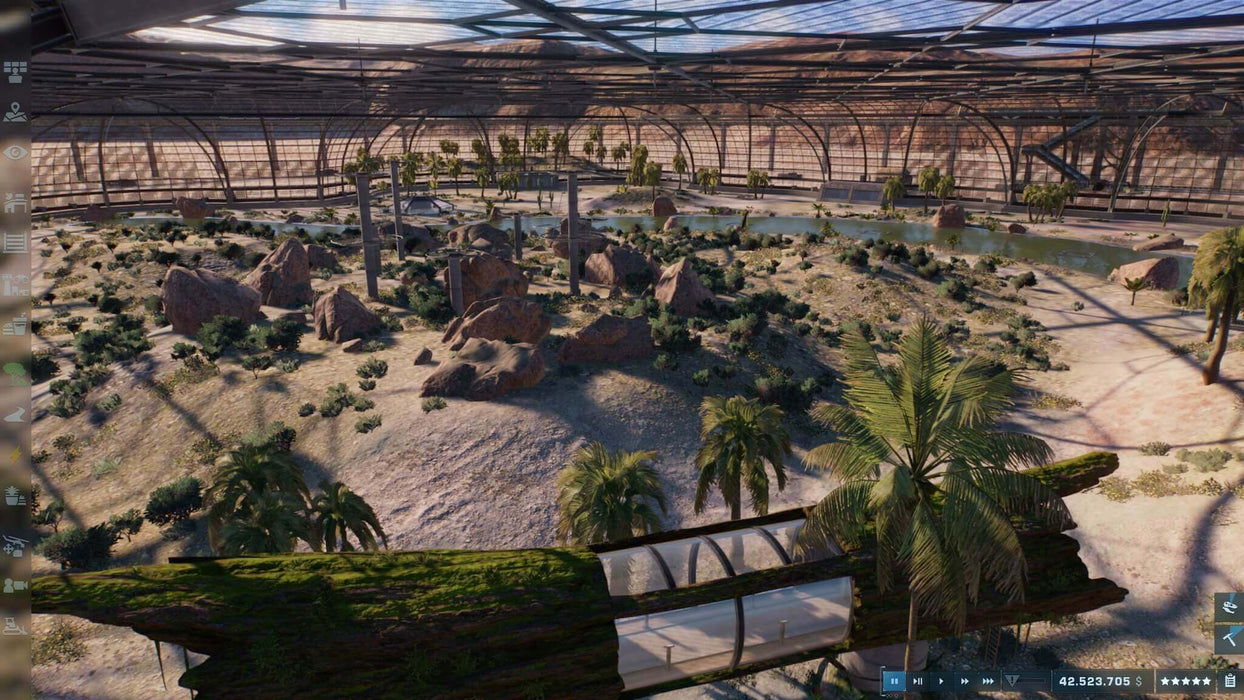 Screenshot from Jurassic World Evolution 2 PC Steam version showcasing a large indoor dinosaur enclosure filled with rocks, water, and vegetation. Create and manage unique biomes—buy your Steam CD Key at RushGame.co