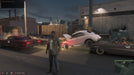 Gameplay scene from Mafia III: Definitive Edition with protagonist Lincoln Clay standing among retro cars in a night-time urban environment. Get the Xbox One/Series X|S digital version today at RushGame.co