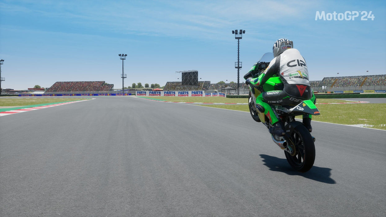 MotoGP 24 PC Steam Gameplay Screenshot – A motorcyclist performs a wheelie while speeding down the racetrack, with a vibrant crowd in the background. Buy MotoGP 24 game keys for PC on Steam at RushGame.co