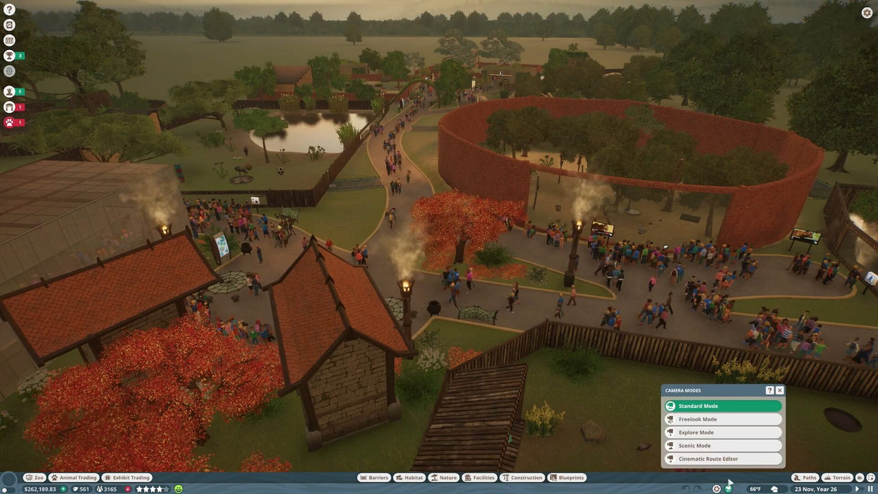 Screenshot from Planet Zoo: Arid Animal Pack DLC on PC Steam showing a large zoo area filled with visitors, animal habitats, and scenic autumn trees. Buy your Planet Zoo game key now at RushGame.co for instant digital delivery