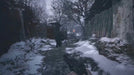 In-game screenshot from Resident Evil Village on PC Steam showing a snowy path and eerie figure ahead, enhancing the chilling atmosphere of the survival horror experience. Buy your digital game key at RushGame.co for instant delivery