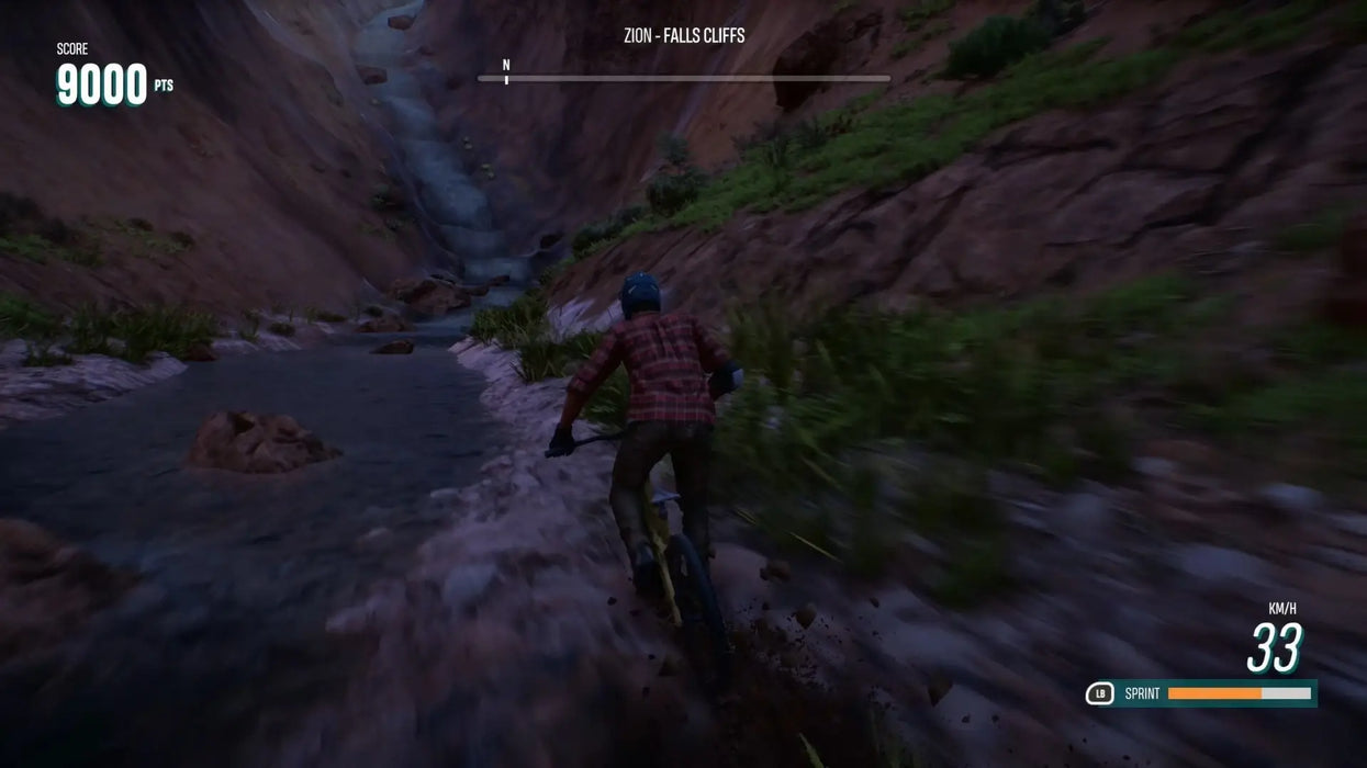 Action-packed Riders Republic Complete Edition screenshot on PC, showing intense mountain biking through a riverbed at Zion Falls Cliffs. Purchase your Ubisoft activation key at RushGame.co