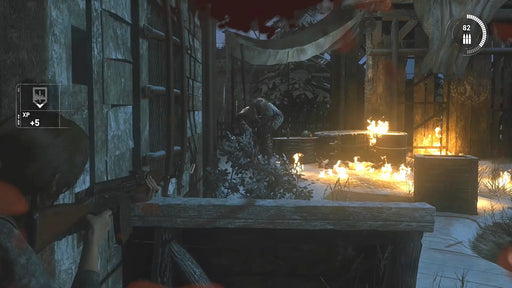 Intense gameplay screenshot from Rise of the Tomb Raider: 20 Year Celebration Edition on XBOX One, showing Lara Croft aiming with a rifle while flames light up a snowy outpost. Get your digital Xbox CD key instantly at RushGame.co and dive into the action