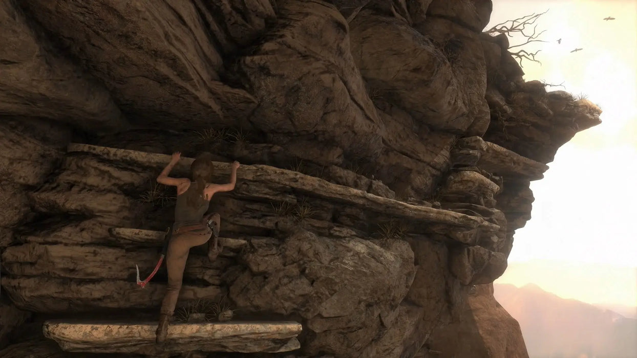 Gameplay image from Rise of the Tomb Raider for PC Steam featuring Lara Croft climbing a rugged cliff face in daylight. Get your Steam game code at RushGame.co and conquer epic adventures