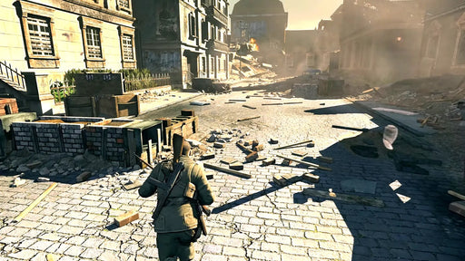 Gameplay screenshot from Sniper Elite V2 Remastered on Xbox One showing the protagonist navigating a devastated European city filled with barricades and rubble. Buy your Xbox One game key at RushGame.co to immerse yourself in the strategic sniping and historic battles of WWII