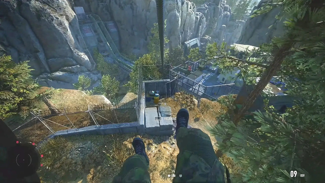 Gameplay screenshot from Sniper Ghost Warrior Contracts 2 Deluxe Arsenal Edition showing a first-person perspective as the player descends a zipline above a military facility nestled in a rocky canyon. Get your Steam key and experience tactical sniping action at RushGame.co
