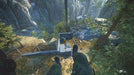 Gameplay screenshot from Sniper Ghost Warrior Contracts 2 Deluxe Arsenal Edition showing a first-person perspective as the player descends a zipline above a military facility nestled in a rocky canyon. Get your Steam key and experience tactical sniping action at RushGame.co